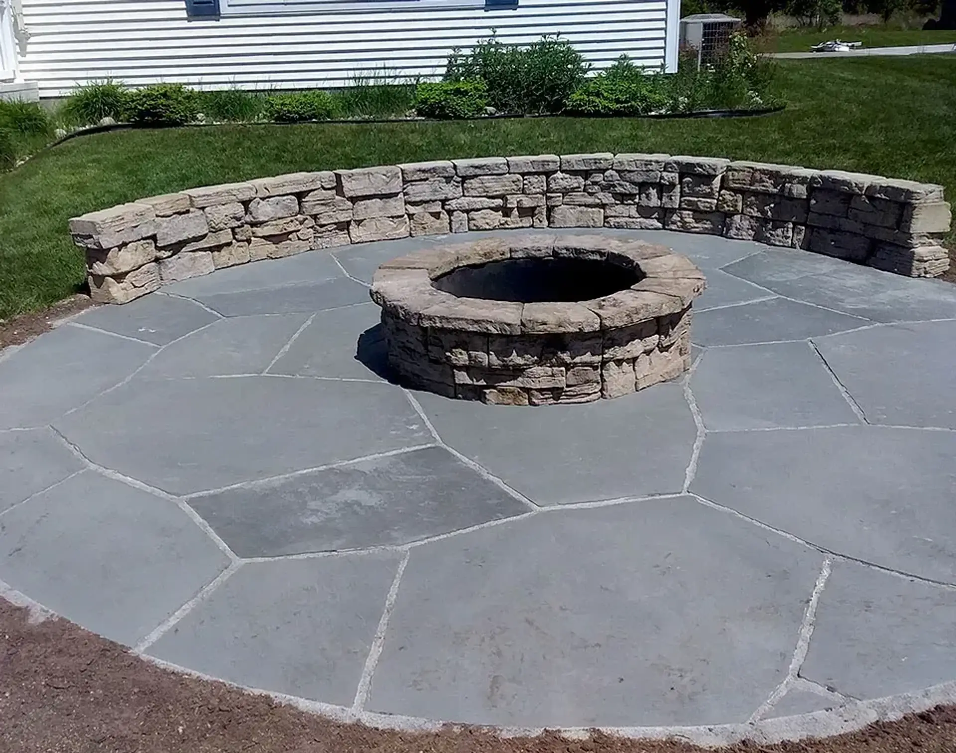 Bluestone flagstone fire pit patio wrapped by a stacked stone seat wall