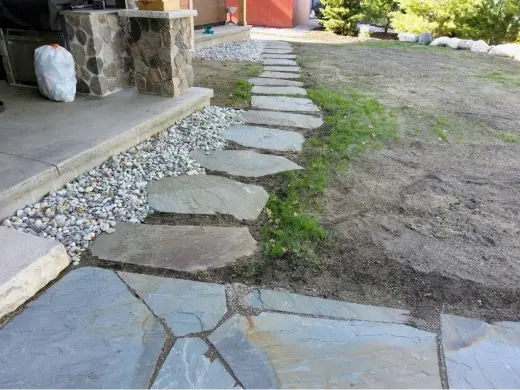Irregular bluestone walkway and stepping stones beside a white river rock bed