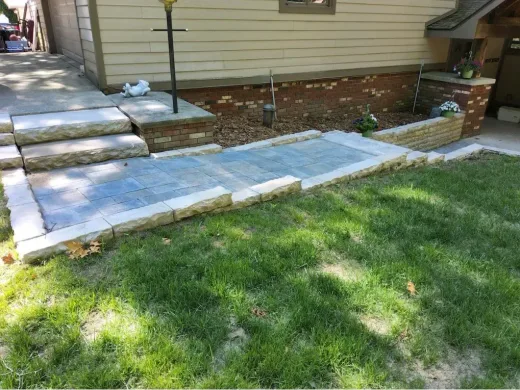 Gray paver walkway edged with limestone blocks and steps beside a house