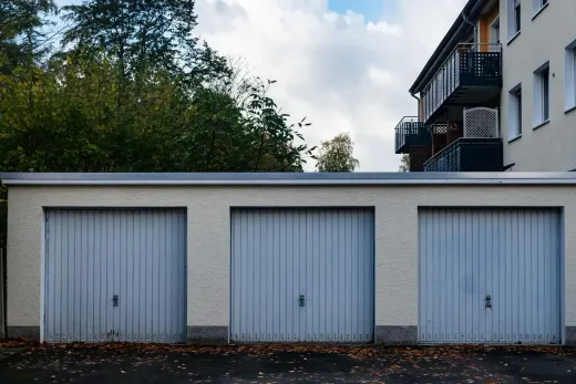 Three gray garage doors on a white block storage garage